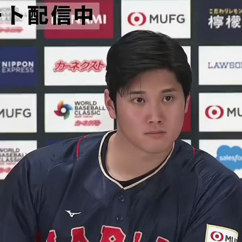 A Man In A Baseball Uniform Stands In Front Of A Wall Of Logos Including One For Mufg GIF