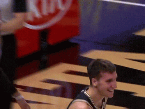 A Man In A Basketball Uniform Is Smiling In Front Of A Sign That Says King GIF