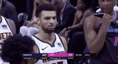 A Man In A Basketball Uniform Is Standing In Front Of A Crowd During A Basketball Game . GIF
