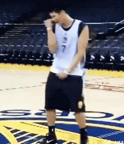 A Man In A Basketball Uniform Is Standing On A Court With His Hands In His Pockets . GIF