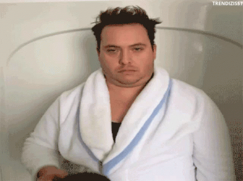 A Man In A Bathrobe Is Sitting In A Bathtub With The Hashtag Trendizisst GIF