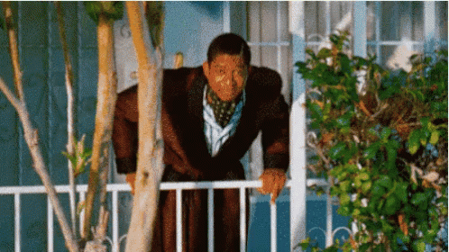 A Man In A Bathrobe Leans Over A Railing GIF