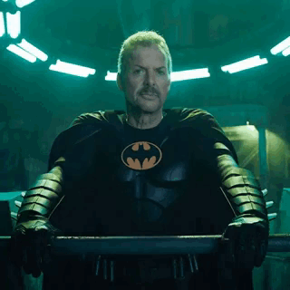 A Man In A Batman Costume Is Standing In A Dark Room . GIF
