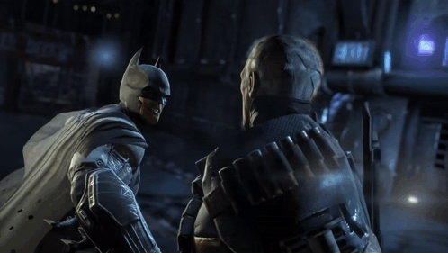A Man In A Batman Costume Talks To Another Man GIF