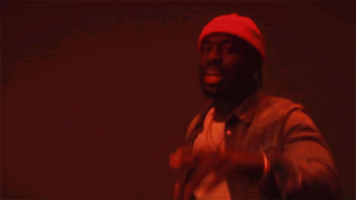 A Man In A Beanie And Leather Jacket Is Dancing GIF