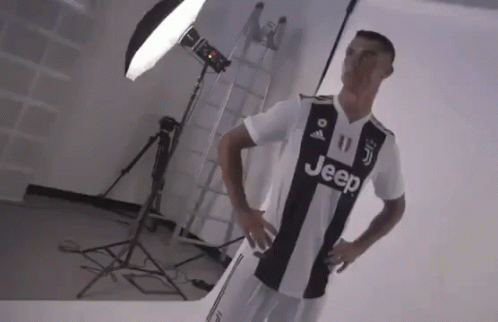 A Man In A Black And White Jeep Jersey Is Standing In Front Of A Light . GIF