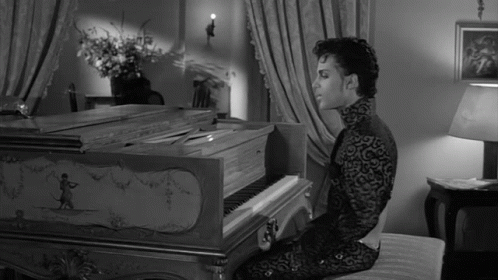 A Man In A Black And White Photo Is Playing A Piano GIF
