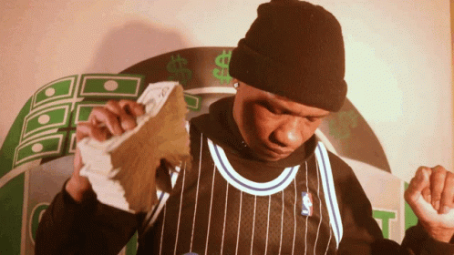 A Man In A Black And White Striped Jersey Holds Up A Stack Of Money GIF