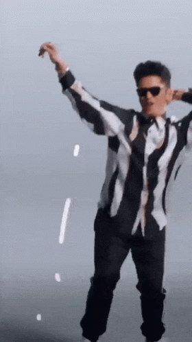 A Man In A Black And White Striped Shirt Is Dancing GIF