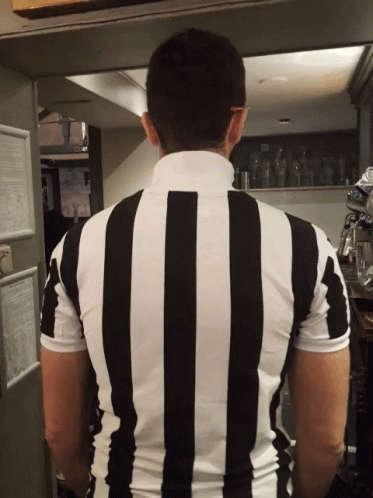A Man In A Black And White Striped Shirt Stands In A Kitchen GIF