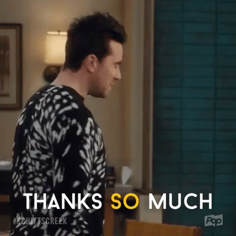 A Man In A Black And White Sweater Is Standing In A Living Room . GIF