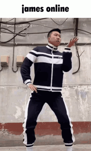 A Man In A Black And White Tracksuit Is Dancing In Front Of A Wall With The Words James Online Above Him GIF