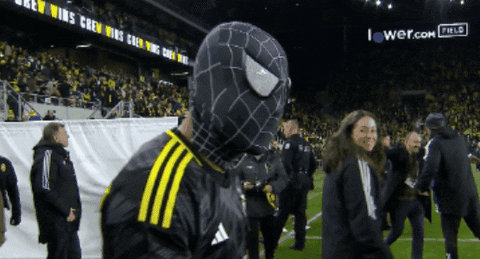 A Man In A Black And Yellow Spider Man Costume Stands On A Field GIF