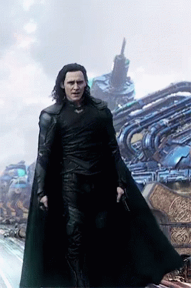 A Man In A Black Cape Is Standing In Front Of A Building GIF