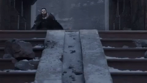 A Man In A Black Cape Is Standing In Front Of A Statue Of A Dragon . GIF
