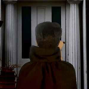 a man in a black cape stands in front of a door talking on a cell phone