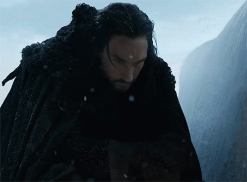 A Man In A Black Cape Stands In Front Of A Mountain GIF