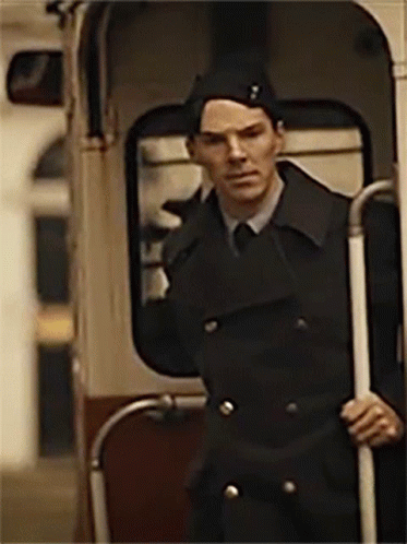 a man in a black coat and hat is standing in a bus