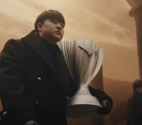 A Man In A Black Coat Holds A Silver Trophy GIF