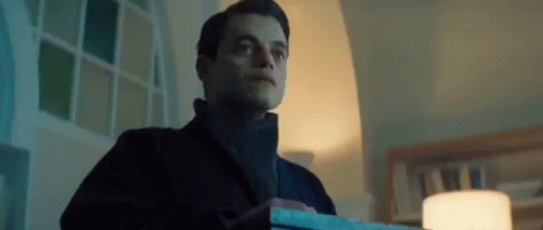 A Man In A Black Coat Is Holding A Box In A Dark Room . GIF
