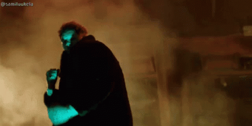 A Man In A Black Coat Is Standing In A Dark Room With Smoke Coming Out Of It And The Hashtag Samiluukela GIF