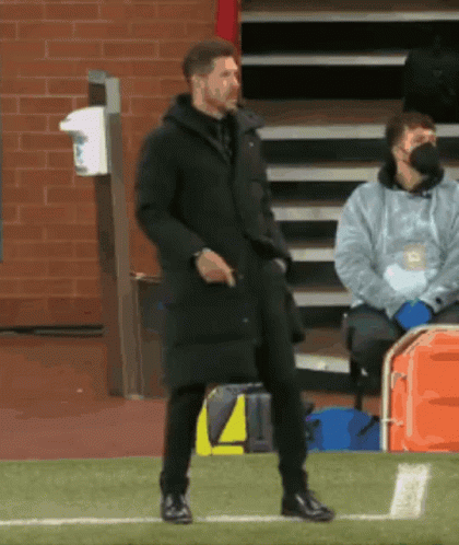 A Man In A Black Coat Is Standing On A Field GIF