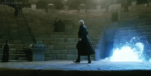 A Man In A Black Coat Is Walking In Front Of Stairs With A Blue Light Coming Out Of Them GIF