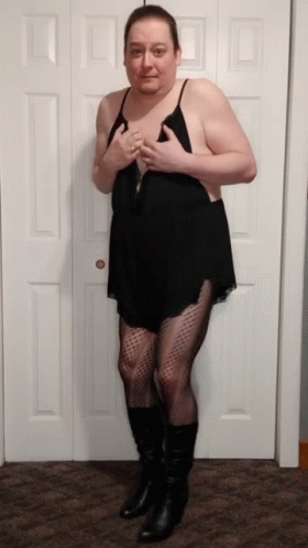 A Man In A Black Dress And Black Boots Stands In Front Of A Door GIF