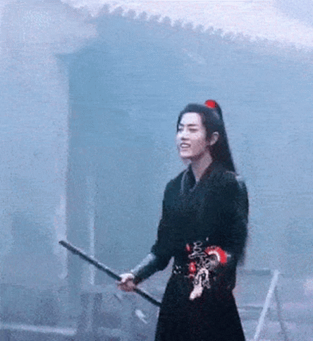 A Man In A Black Dress Is Holding A Sword In His Hand . GIF