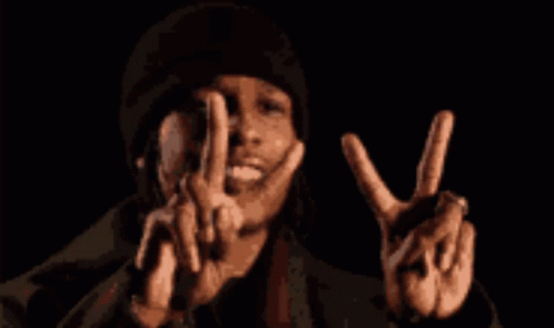 A Man In A Black Hat Is Making A Peace Sign With His Hands GIF