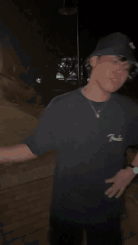A Man In A Black Hat Is Shaking Hands With Another Man In A Dark Room . GIF