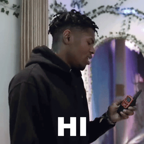 a man in a black hoodie is holding a cell phone with the word hi on it