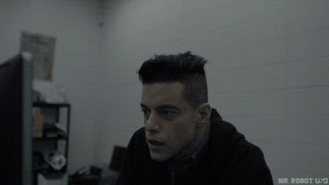 A Man In A Black Hoodie Is Sitting In Front Of A Computer Screen . GIF