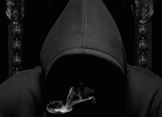 A Man In A Black Hoodie Is Smoking A Cigarette In A Black And White Photo . GIF