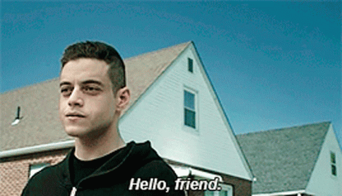 A Man In A Black Hoodie Says Hello Friend In Front Of A House GIF