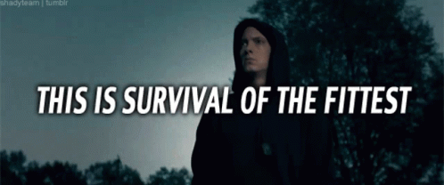 A Man In A Black Hoodie Stands In Front Of Trees With The Words " This Is Survival Of The Fittest " GIF