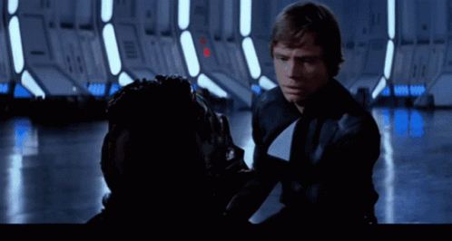 A Man In A Black Jacket And Tie Is Talking To Another Man GIF