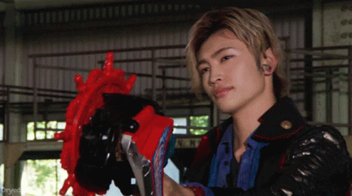 A Man In A Black Jacket Holds A Red Object In His Hands GIF