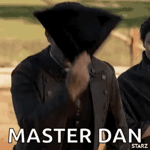 A Man In A Black Jacket Is Covering His Face With A Black Hat And Says `` Master Dan '' . GIF