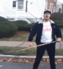 A Man In A Black Jacket Is Holding A Hula Hoop In Front Of A House GIF