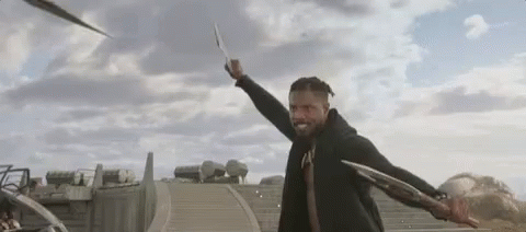 A Man In A Black Jacket Is Holding A Sword In His Hand . GIF