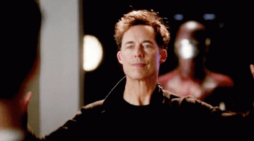 A Man In A Black Jacket Is Raising His Hands In The Air . GIF