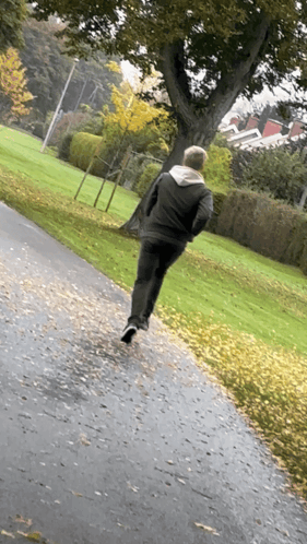 A Man In A Black Jacket Is Running Down A Path GIF