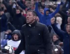 A Man In A Black Jacket Is Screaming In Front Of A Crowd That Is Cheering GIF