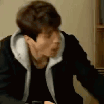 A Man In A Black Jacket Is Sitting At A Table With His Mouth Open . GIF