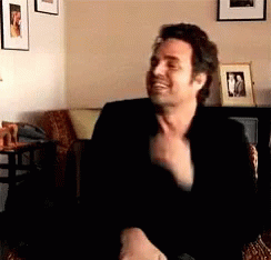 A Man In A Black Jacket Is Sitting In A Wicker Chair GIF