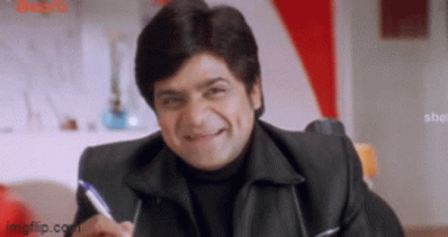 A Man In A Black Jacket Is Smiling And Holding A Pen In His Hand . GIF