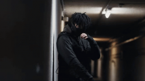 A Man In A Black Jacket Is Standing In A Dark Room GIF