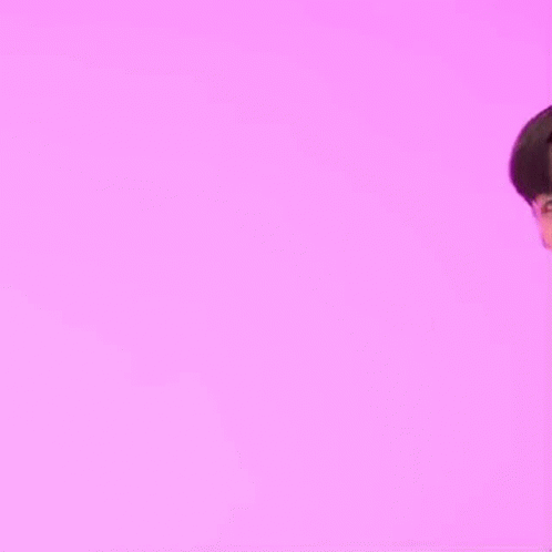 A Man In A Black Jacket Is Standing In Front Of A Pink Background . GIF