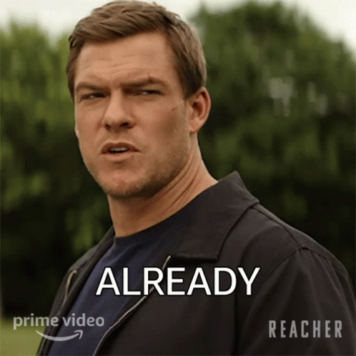 A Man In A Black Jacket Is Standing In Front Of A Sign That Says " Already " GIF